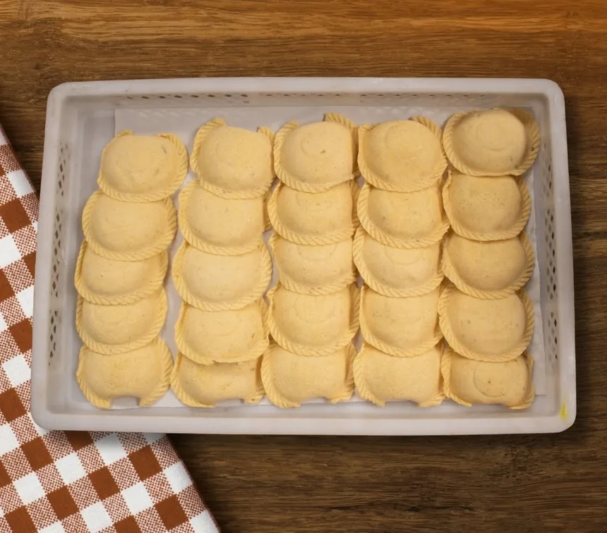 Bandeja de empanadas crudas de Pastas Greli dentro de una caja de reparto
