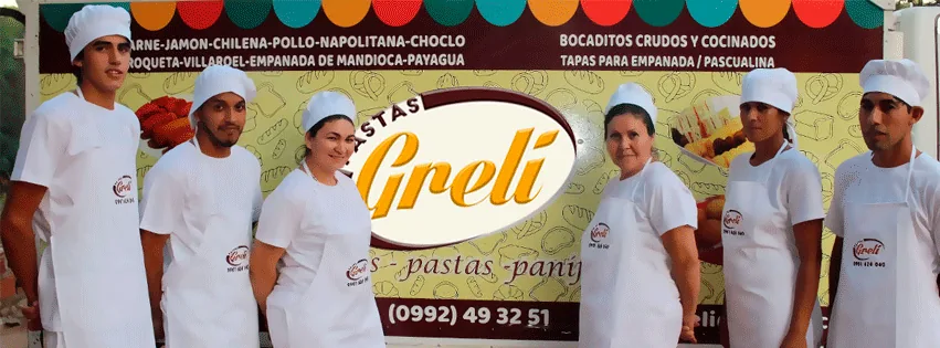 Seis personas del equipo de Pastas Greli con uniforme blanco, delantal y gorro, delante del camión