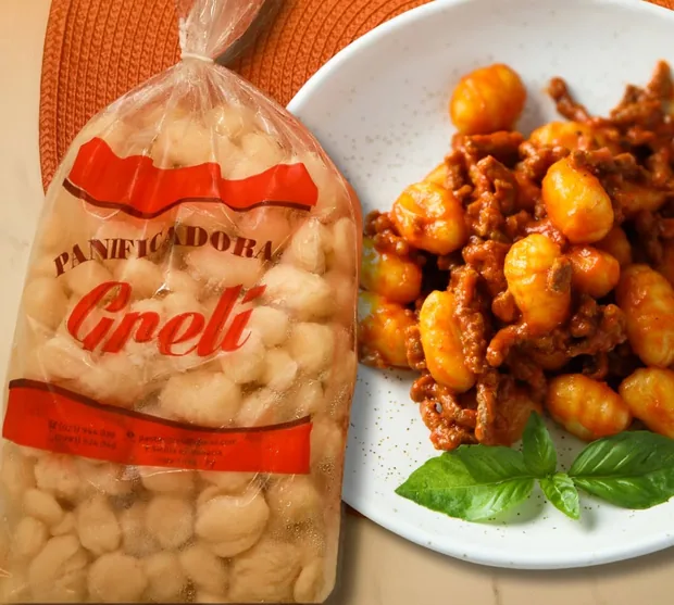 Bolsa de ñoquis Panificadora Greli junto a un plato de ñoquis con salsa