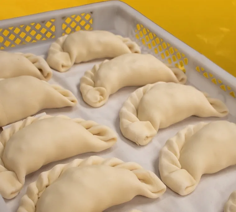 Empanadas de repulgue crudas sobre papel, en una caja de reparto